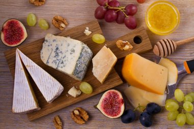 Ahşap rustik zemin üzerine peynir seçimi. Peynir tabağı farklı peynir, üzüm, incir, fındık ve bal ile servis ile. Yiyecek şarap