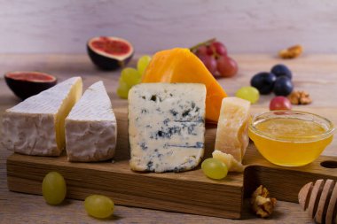 Ahşap rustik zemin üzerine peynir seçimi. Peynir tabağı farklı peynir, üzüm, incir, fındık ve bal ile servis ile. Yiyecek şarap