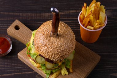 (Bıçak ile) ev yapımı üçlü katlı hamburger ve patates kızartması koyu ahşap zemin üzerinde. Yukarıdan görüntülemek, top, yatay