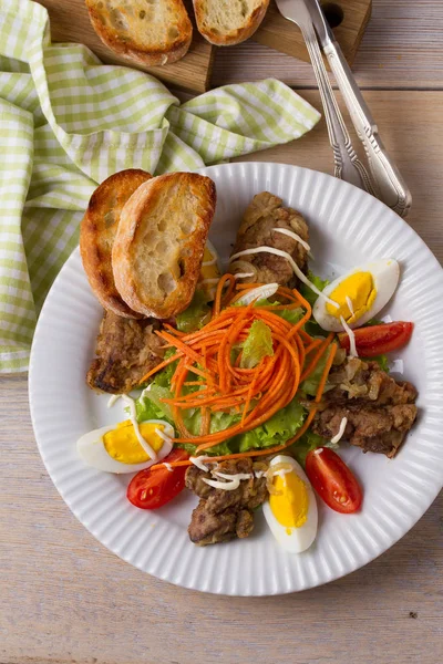 Chicken liver, carrot, eggs, tomatoes, lettuce and fried onion salad. Liver and vegetables. Top, overhead, above view, vertical