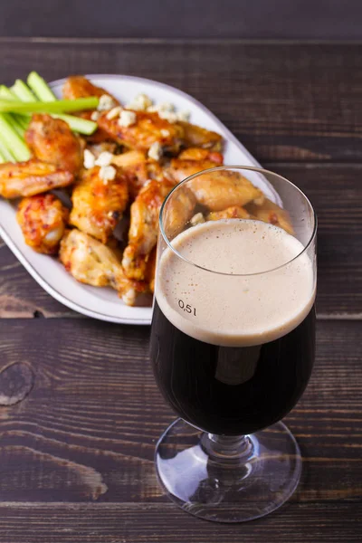 Beer and chicken wings buffalo with blue cheese and celery sticks, vertical