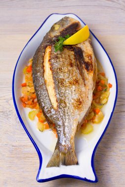 Bütün kılıçbalığı veya dorada balık sebze, kekik ve limon, dikey