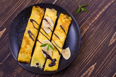 Ev yapımı krep muz, çikolata ve nane ile servis tatlı beyaz peynir dolu. Kaydırılan krep. Tepegöz, yukarıda, sayfa görünümü