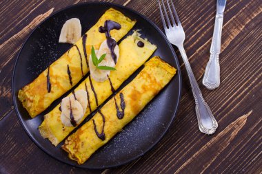 Ev yapımı krep muz, çikolata ve nane ile servis tatlı beyaz peynir dolu. Kaydırılan krep. Tepegöz, yukarıda, sayfa görünümü