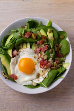 Sahanda yumurta pastırma, quinoa, avokado, ıspanak ve kahvaltı için kabak çekirdeği