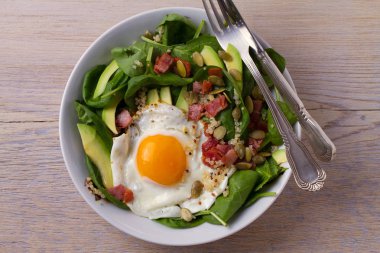 Sahanda yumurta pastırma, quinoa, avokado, ıspanak ve kahvaltı için kabak çekirdeği