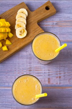 Mango muz smoothie ahşap arka plan üzerinde. Yukarıdan görüntülemek, top, dikey