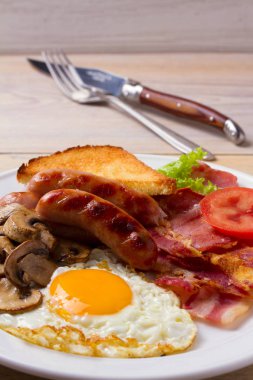 Geleneksel İngilizce veya İrlandalı kahvaltı: sosis, pastırma, yumurta, mantar, domates ve tost. Besleyici sabah yemek. dikey