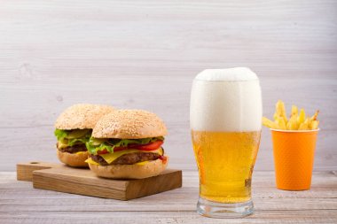Bardak bira hamburger ve patates kızartması ahşap arka plan ile. Bira ve gıda kavramı. Ale ve gıda. metin için yatay, yer