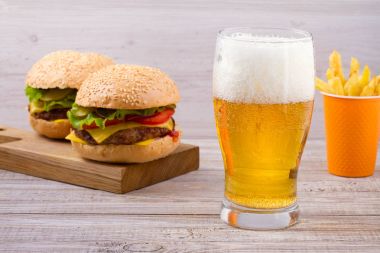Bardak bira hamburger ve patates kızartması ahşap arka plan ile. Bira ve gıda kavramı. Ale ve gıda, yatay
