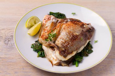 Ispanaklı kavrulmuş çipura. Dorado veya dorada balık fileto beyaz plaka üzerinde