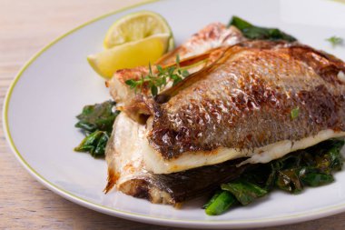 Ispanaklı kavrulmuş çipura. Dorado veya dorada balık fileto beyaz plaka üzerinde