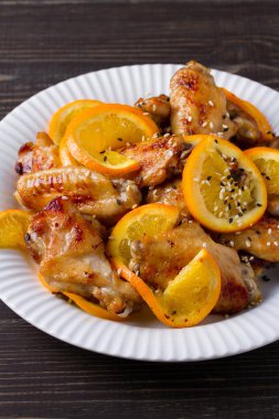 Tatlı ve ekşi tavuk kanadı ile portakal, hizmet ile susam beyaz plaka üzerinde