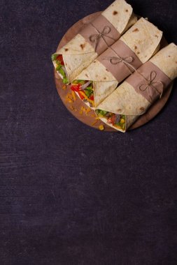 Tortilla, burrito, bükülmüş sandviç rulo. Sığır eti, domates, marul, salatalık, kaşar peynir, Mısır ve soğan halkaları sarar. Yukarıdan görüntülemek, top, dikey