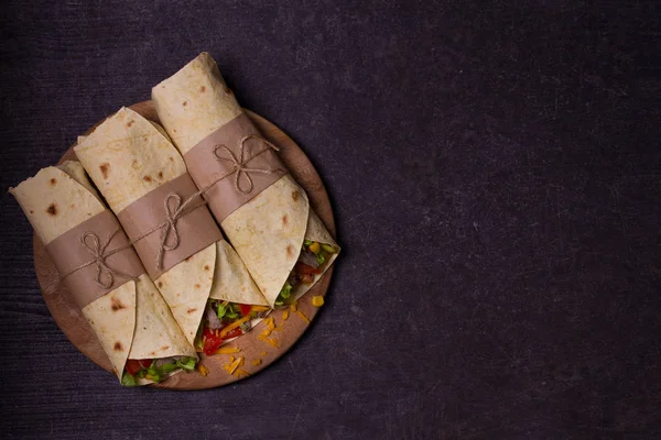 Tortilla, burrito, bükülmüş sandviç rulo. Sığır eti, domates, marul, salatalık, kaşar peynir, Mısır ve soğan halkaları sarar. Yukarıdan görüntülemek, top, yatay