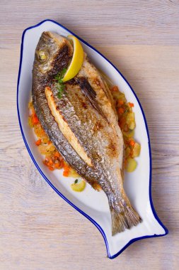 Havuç, soğan ve kereviz saplarını üzerinde ızgara çupra