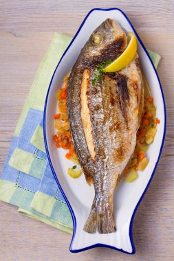 Havuç, soğan ve kereviz saplarını üzerinde ızgara çupra