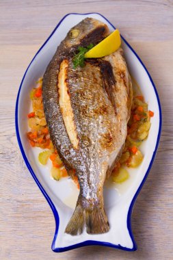 Havuç, soğan ve kereviz saplarını üzerinde ızgara çupra