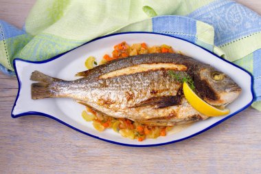 Havuç, soğan ve kereviz saplarını üzerinde ızgara çupra