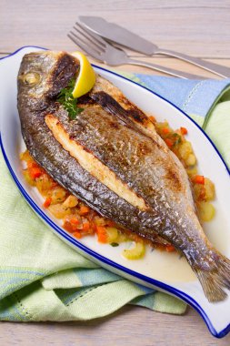 Havuç, soğan ve kereviz saplarını üzerinde ızgara çupra