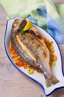 Havuç, soğan ve kereviz saplarını üzerinde ızgara çupra