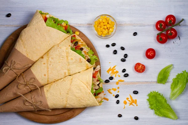 Tavuk, domates, marul, siyah fasulye, kaşar peyniri ve tatlı Mısır ile tamamladı. Tortilla, burrito, bükülmüş sandviç rulo. Yukarıdan görüntülemek, top, yatay