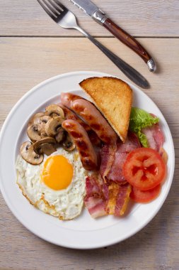 Tam İngilizce veya İrlandalı kahvaltı: sosis, pastırma, yumurta, mantar, domates ve tost. Besleyici sabah yemek