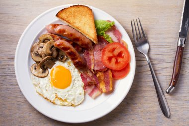 Tam İngilizce veya İrlandalı kahvaltı: sosis, pastırma, yumurta, mantar, domates ve tost. Besleyici sabah yemek