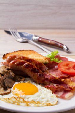 Tam İngilizce veya İrlandalı kahvaltı: sosis, pastırma, yumurta, mantar, domates ve tost. Besleyici sabah yemek