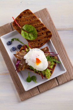 Haşlanmış yumurta, pastırma, ezilmiş beyaz fasulye ve avokado tost. Sandviç. Yukarıdan görüntülemek, top, dikey