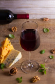 Víno a sýr. Sklenice na víno se sýrem, ořechy a bazalka na dřevěné pozadí. Víno a jídlo koncept