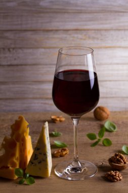 Şarap ve peynir. Şarap kadehi ile peynir, fındık ve fesleğen ahşap arka plan üzerinde. Yemek ve şarap kavramı