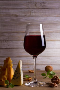 Şarap ve peynir. Şarap kadehi ile peynir, fındık ve fesleğen ahşap arka plan üzerinde. Yemek ve şarap kavramı