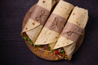 Sığır eti, domates, marul, salatalık, peynir ve Mısır kesme tahtası üzerinde ile tamamladı. Tortilla, burrito, bükülmüş sandviç rulo. 
