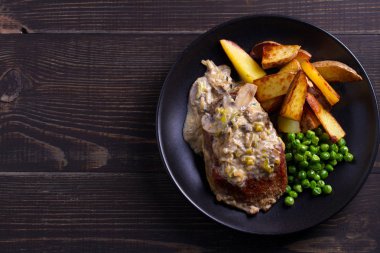 Sığır eti biftek mantar krema sos, patates dilimleri ve yeşil bezelye. Yukarıdan görüntülemek, top 