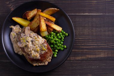 Sığır eti biftek mantar krema sos, patates dilimleri ve yeşil bezelye. Yukarıdan görüntülemek, top 