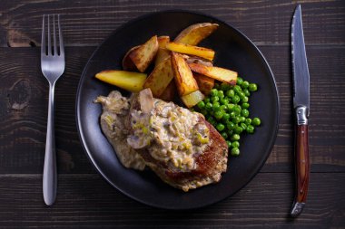 Sığır eti biftek mantar krema sos, patates dilimleri ve yeşil bezelye. Yukarıdan görüntülemek, top 