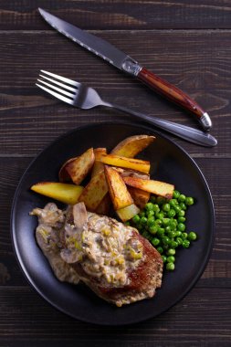 Sığır eti biftek mantar krema sos, patates dilimleri ve yeşil bezelye. Yukarıdan görüntülemek, top 