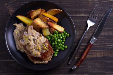 Sığır eti biftek mantar krema sos, patates dilimleri ve yeşil bezelye. Yukarıdan görüntülemek, top 