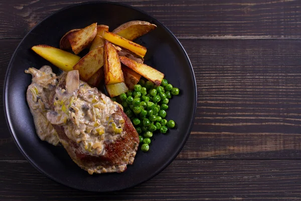 Sığır eti biftek mantar krema sos, patates dilimleri ve yeşil bezelye. Yukarıdan görüntülemek, top 