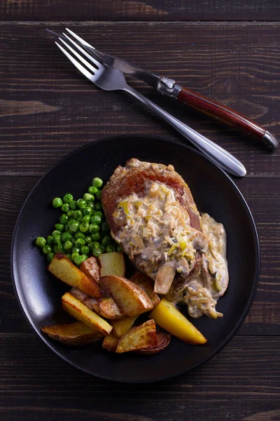Sığır eti biftek mantar krema sos, patates dilimleri ve yeşil bezelye. Yukarıdan görüntülemek, top 
