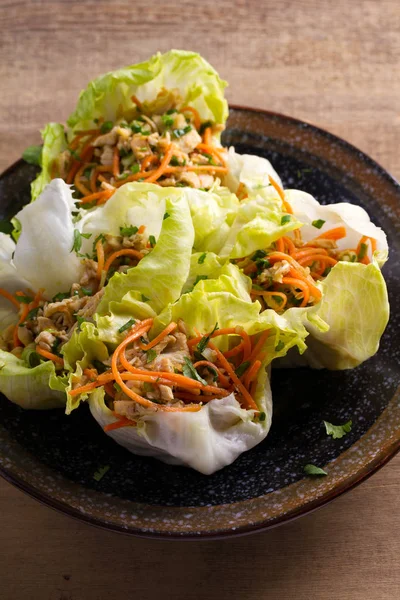 Lettuce wraps with chicken, carrot, peanuts and scallion. Stuffed iceberg lettuce leaves with chicken