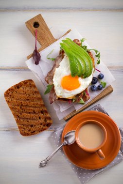 Avokado, yumurta ve pastırma sandviç. Sahanda yumurta ve tost avokado. Panini. Kahvaltı veya brunch için sağlıklı lezzetli yemekler