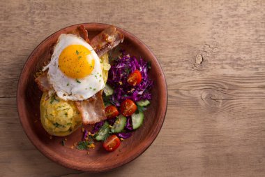 Ceketli fırında patates peynir ile yüklenen ve pastırma ile tepesinde ve sebze ile plaka üzerinde yumurta kızarmış. Tepesi ile doldurulmuş patates. Yukarıdan görüntülemek, top, ek yükü 