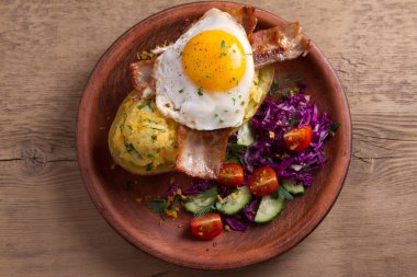 Ceketli fırında patates peynir ile yüklenen ve pastırma ile tepesinde ve sebze ile plaka üzerinde yumurta kızarmış. Tepesi ile doldurulmuş patates. Yukarıdan görüntülemek, top, ek yükü 