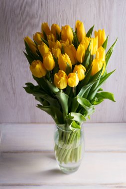 Buket bahar Lale çiçek Vazoda beyaz ahşap zemin üzerinde. Sarı laleler