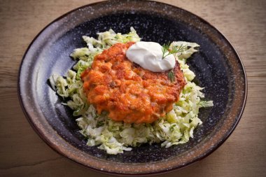 Somon burger ve lahana salatası kase ahşap masa üzerinde. Somon Balık köftesi ve sebze. Yatay