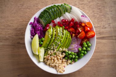 Vejetaryen sağlıklı gıda: quinoa, avokado, nar, domates, yeşil bezelye, turp, ahşap masa ıslak zeminde kırmızı lahana ve limon salata. Tepegöz, yatay