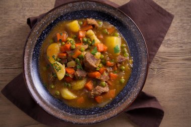Güveç, sığır eti, patates, havuç ve yeşil bezelye ile yaptı. Ahşap masa üzerinde bir kasede gulaş çorbası. Tepegöz, yatay