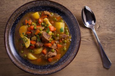 Güveç, sığır eti, patates, havuç ve yeşil bezelye ile yaptı. Ahşap masa üzerinde bir kasede gulaş çorbası. Tepegöz, yatay